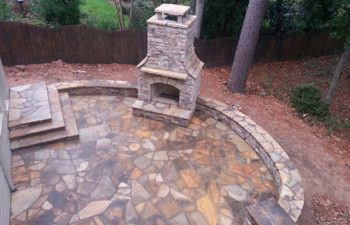 a flagstone patio with an outdoor stone fireplace